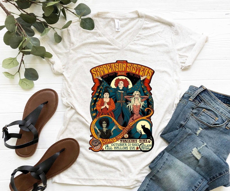 Pu&ograve; includere: Una maglietta bianca con una grafica in stile vintage delle sorelle Sanderson del film Hocus Pocus. La grafica presenta le tre sorelle nei loro costumi iconici, con il testo "Sanderson Sisters" e "Back From The Dead" sopra di loro. Il testo "Billy Butcherson" e "Thackerx - Binx" &egrave; sotto le sorelle, insieme alla data "October 31, 1993" e alla localit&agrave; "Salem, Mass."
