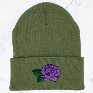 May include: A green knitted beanie with a purple embroidered rose on the cuff.