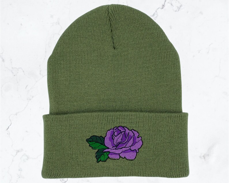 May include: A green knitted beanie with a purple embroidered rose on the cuff.