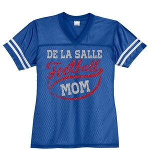 May include: Blue and white football jersey with the text "DE LA SALLE Football MOM" in silver glitter and red lettering.