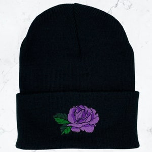 May include: Black beanie with a purple embroidered rose on the front.