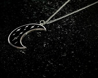 May include: A silver chain necklace with a black crescent moon pendant. The moon has a silver outline and white stars inside.