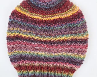 May include: A colourful striped knitted beanie hat with a variety of colours including red, yellow, purple, and green.