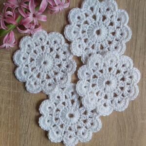 May include: Four white crocheted doilies with a delicate floral design.