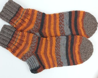 May include: A pair of striped socks in brown, orange, and gray. The socks are knitted and have a ribbed texture.