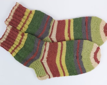 May include: A pair of striped socks in shades of green, red, yellow, and beige. The socks are knitted and have a textured appearance.
