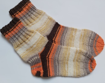 May include: A pair of knitted socks in a brown, orange, and white striped pattern.