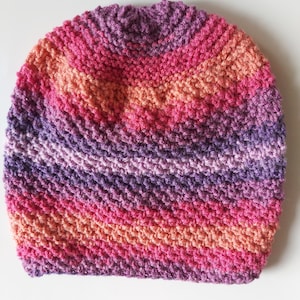May include: A purple, pink, and orange striped knitted beanie hat.