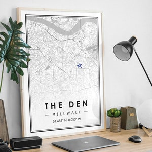 Peut inclure: Une impression de carte en noir et blanc encadrée avec une étoile bleue marquant un emplacement. L'impression porte le texte "THE DEN - MILLWALL - 51.485° N, 0.050° W" en bas.