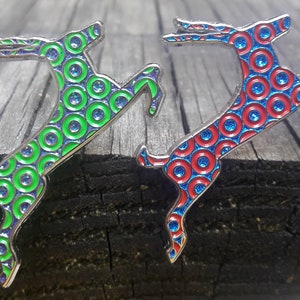 May include: Two silver jumping deer pins with a circle pattern. One deer is green with blue circles and the other is red with blue circles.