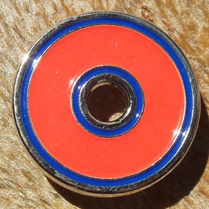 May include: A round, silver-colored metal disc with a red center and two blue rings. The center has a smaller hole.