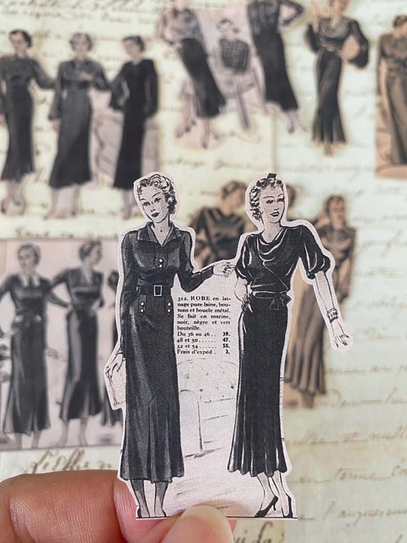 May include: Two vintage illustrations of women wearing black dresses. The illustrations are printed on a white background with text describing the dress fabric and sizes. The text reads: "312. ROBE en las nage pure laine, boutons et boucle m&eacute;tal. Se fait en marine, noir, n&egrave;gre et vert bouteille. Du 36 au 46... 39. 48 et 50... 47. 54 et 54... 55. Frais d'exp&eacute;d. 1."