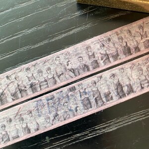 May include: Two rolls of pink washi tape featuring a vintage black and white image of people in a line. The tape has a subtle pink border.