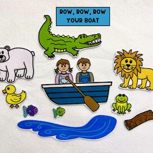 May include: A felt board set featuring a blue boat with two children, a green alligator, a yellow lion, a polar bear, a yellow duck, a green frog, two fish, a log, and blue water. The text "ROW, ROW, ROW YOUR BOAT" is in a blue box.