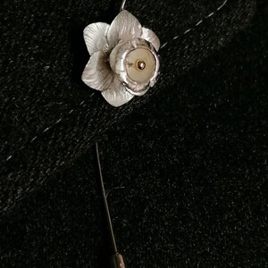 Puede incluir: Broche de narciso de plata con un centro dorado. La broche est&aacute; unida a un alfiler de plata.