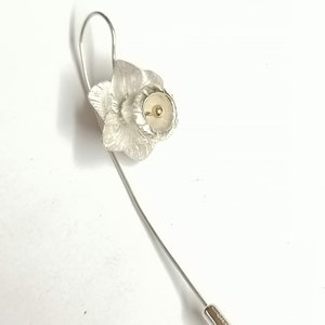 Puede incluir: Broche de narciso de plata con un centro dorado. La broche tiene un alfiler largo y delgado.