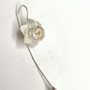 Puede incluir: Broche de narciso de plata con un centro dorado. La broche tiene un alfiler largo con una tapa de plata que dice "Silver."