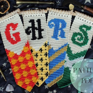 May include: Four crocheted banners with the Hogwarts house crests and initials: Gryffindor, Hufflepuff, Ravenclaw, and Slytherin. The banners are white with colored details and are hanging from wooden dowels. The text "PATTERN PDF" is visible in the bottom right corner.