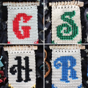 May include: Four handmade wall hangings with different colored letters. The letters are G, S, H, and R. The hangings are made of white yarn with the letters woven in.