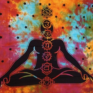 May include: A tie-dye tapestry with a vibrant blend of orange, pink, and blue hues. A black silhouette of a person in a seated yoga pose is centered, with chakra symbols aligned along the body. Black star shapes are scattered across the background.