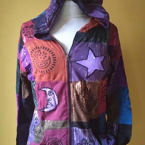 Puede incluir: Una sudadera con capucha de patchwork con cremallera frontal, con una variedad de colores y patrones. La chaqueta incluye una capucha y bolsillos. Los diseños aplicados incluyen una luna creciente, una estrella y otros motivos decorativos.