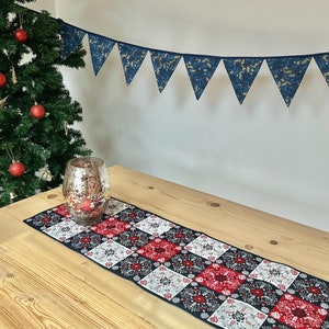 Peut inclure: Un chemin de table à carreaux rouges et blancs avec un fond noir et un motif floral. Le chemin de table est sur une table en bois avec un bougeoir en argent.