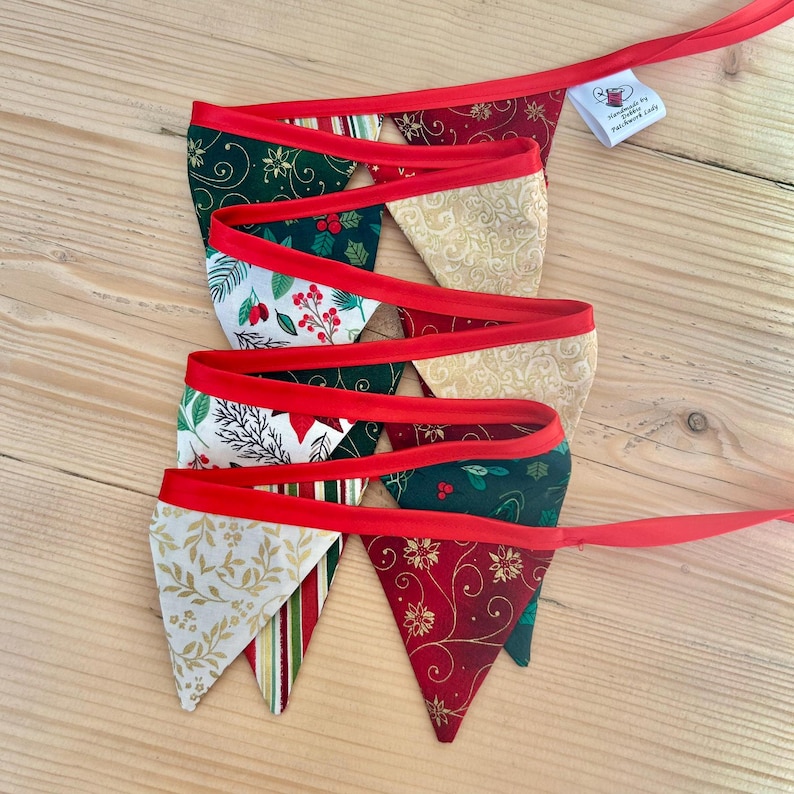 May include: A red and green Christmas bunting with a variety of festive patterns, including holly, snowflakes, and swirls. The bunting is handmade by "Handmade by Patchwork Lady".
