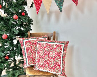 A pair of Christmas cushions in red and green festive holly floral fabric