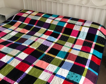 May include: A colorful patchwork quilt with a black, white, green, red, pink, purple, blue, and yellow plaid pattern. The quilt is made of various fabrics with different textures and patterns.