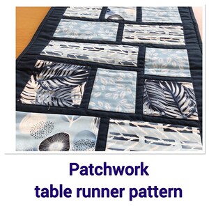 May include: A patchwork table runner pattern with a navy blue background and blue and white fabric squares. The fabric squares feature different patterns, including leaves, dots, and stripes.