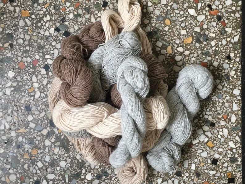 Puede incluir: Un mont&oacute;n de hilo en varios tonos de marr&oacute;n, beige y gris. El hilo est&aacute; dispuesto en un mont&oacute;n suelto y enredado.