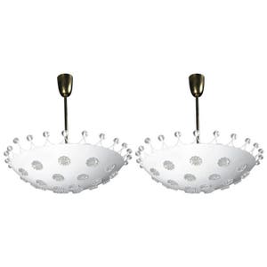 Peut inclure: Deux luminaires de plafond ronds blancs avec une finition en laiton. Chaque luminaire a un abat-jour circulaire en verre blanc dépoli avec un motif de petites fleurs en verre clair. Les abat-jours sont entourés d'une couronne de perles de verre transparentes.
