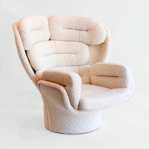 Puede incluir: Un sillón blanco de felpa con un diseño orgánico único. El sillón tiene un respaldo alto y un asiento redondeado con múltiples cojines. El sillón está hecho de una tela suave y esponjosa.