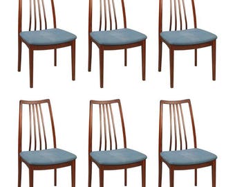 Könnte beinhalten: Sechs Esszimmerstühle im Mid-Century-Modern-Stil mit einem dunklen Holzrahmen und blauer Polsterung.