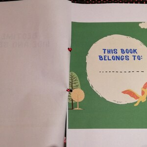 May include: A green book cover with a white circle and the text "This book belongs to:"  The circle has a dashed line for writing a name.  There are two dinosaurs, one orange and one blue, on the cover.