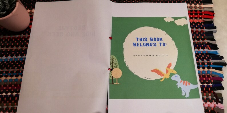 May include: A green book cover with a white circle and the text "This book belongs to:"  The circle has a dashed line for writing a name.  There are two dinosaurs, one orange and one blue, on the cover.