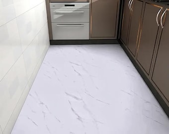 May include: White marble-patterned flooring in a kitchen setting. The floor has a glossy finish with gray veining. The kitchen features brown cabinets with gold trim, a white oven, and white tiled walls. The overall design is modern and clean.
