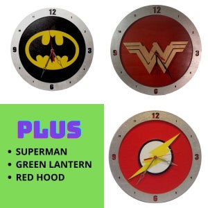 Puede incluir: Cuatro relojes redondos con logotipos de superhéroes. Los relojes representan a Batman, Wonder Woman, Flash y Superman. Los relojes son todos plateados con números y manecillas negros.