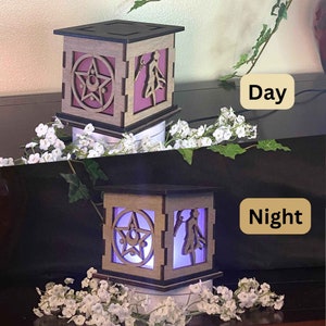May include: Two wooden light-up boxes with a star and a figure inside. The box on the left is lit with a pink light and the box on the right is lit with a purple light. The text "Day" is above the left box and the text "Night" is above the right box.
