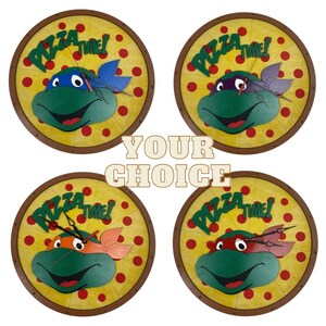 May include: Four round wall clocks featuring Teenage Mutant Ninja Turtles characters. Each clock has a yellow background with red pizza slices and a green turtle head with a different colored bandana. The text "Pizza Time!" is written in a white arc around the turtle head.