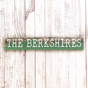 May include: A wooden sign with a green background and white text that reads "THE BERKSHIRES".