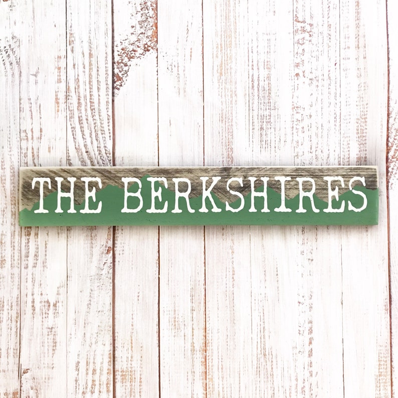 May include: A wooden sign with a green background and white text that reads "THE BERKSHIRES".