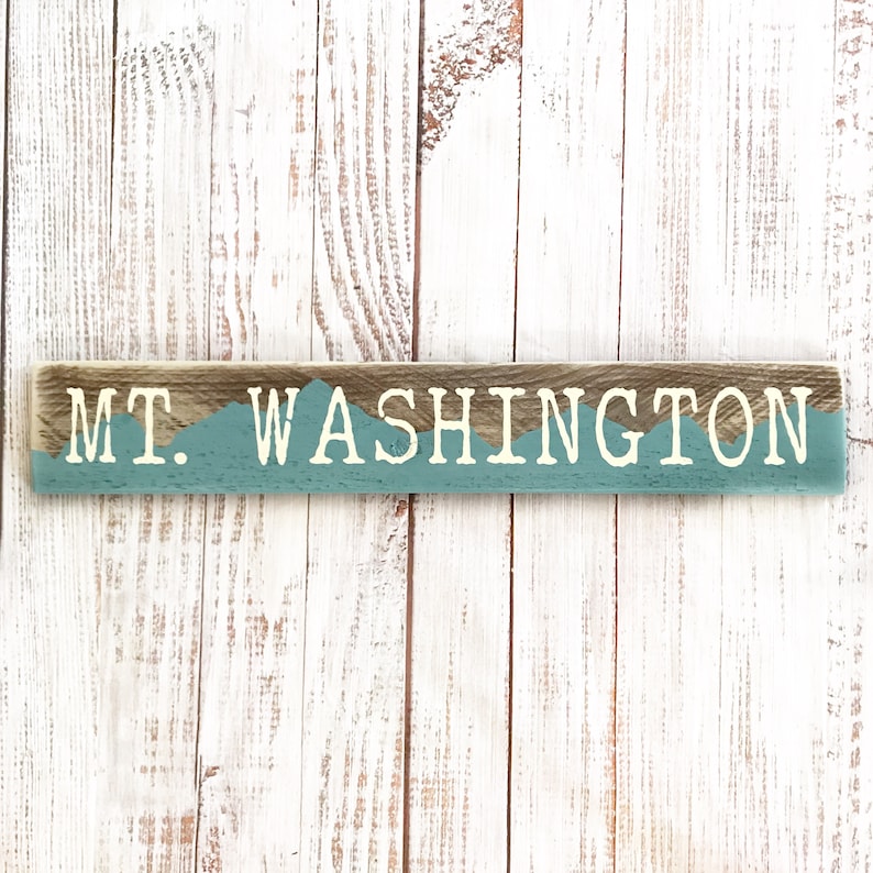 May include: Wooden sign with the text "MT. WASHINGTON" in white letters on a blue background. The sign has a rustic, weathered look.