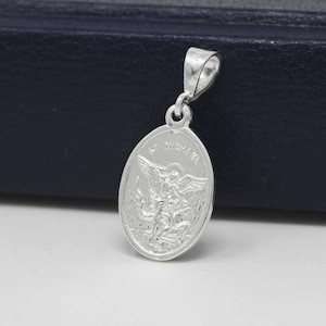 May include: Silver pendant featuring a detailed image of Saint Michael the Archangel with the words "St. Michael" inscribed around the oval-shaped pendant.