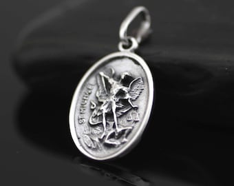 May include: Silver pendant featuring a detailed depiction of Saint Michael the Archangel, with the inscription "St. Michael" on the side.