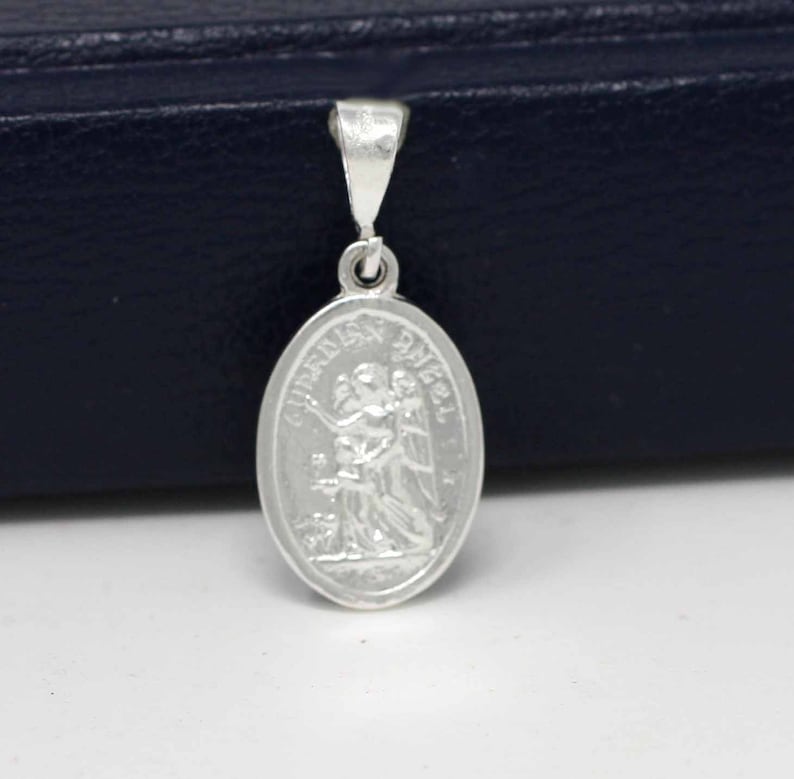 May include: Silver pendant featuring a guardian angel with the words "Guardian Angel" inscribed around the oval-shaped charm.