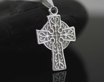 May include: A silver Celtic cross pendant with intricate knotwork design. The cross is on a black background.