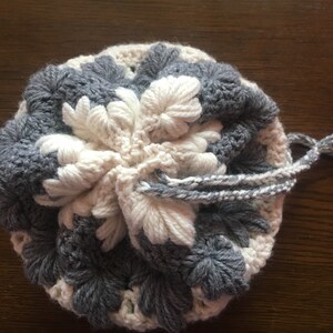 Peut inclure: Un sac à cordon crocheté avec un motif floral blanc et gris.