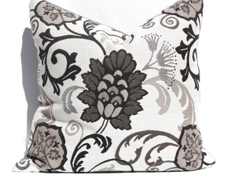 May include: A white pillow with a black and gray floral pattern. The pillow is made of a soft, textured fabric.