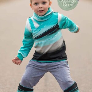 May include: A young boy wearing a teal, black, and white striped long-sleeved shirt with a high neck and gray sweatpants with teal, black, and white stripes on the legs. The boy is standing on a paved surface. The image includes the text "Carter's Room".